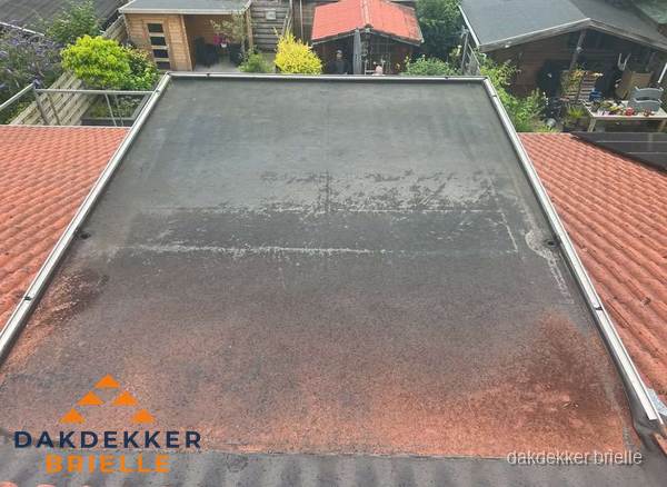 Verouderd plat dak met slijtage tussen schuine daken in Brielle Verouderd plat dak met slijtage tussen schuine daken in Brielle