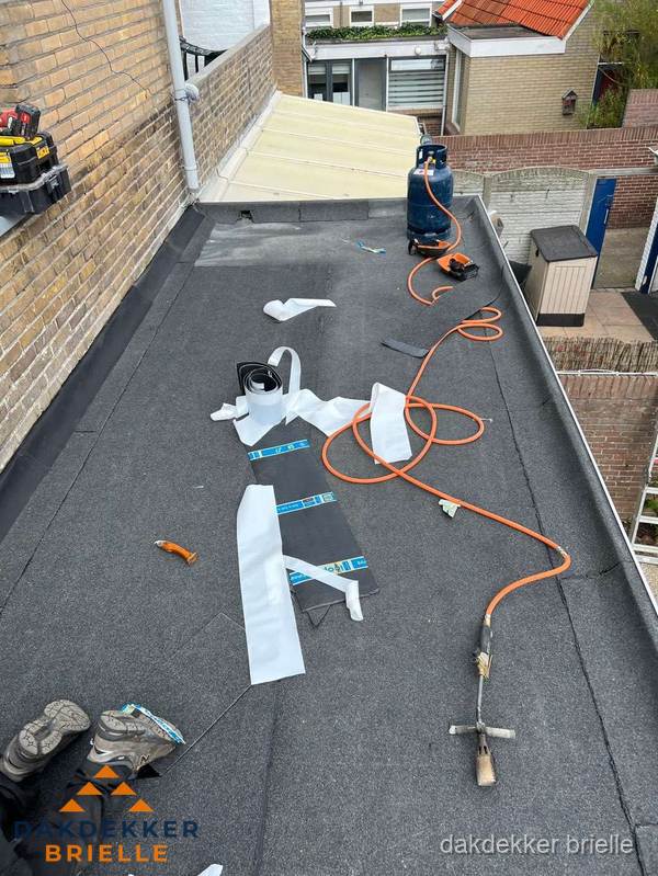 Dakdekkers bezig met bitumen dakbedekking in Brielle